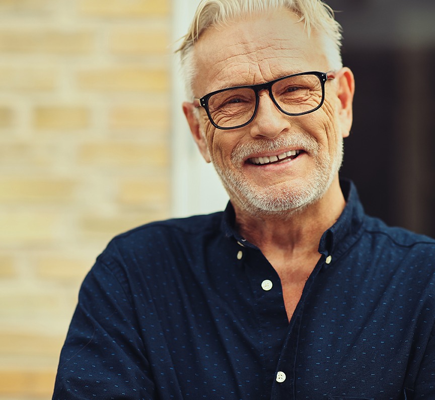 Laughing senior man standing in his yard at home