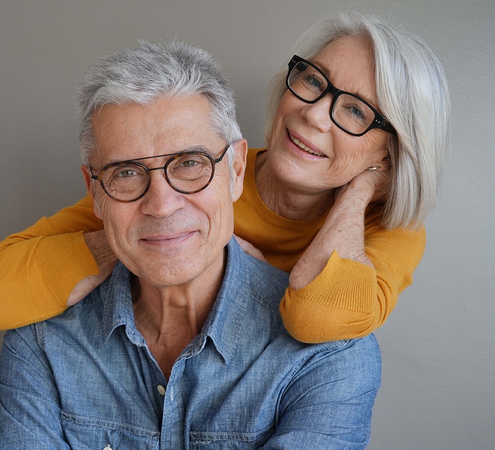 Portrait of relaxed fun senior couple wearing glasses on backgr